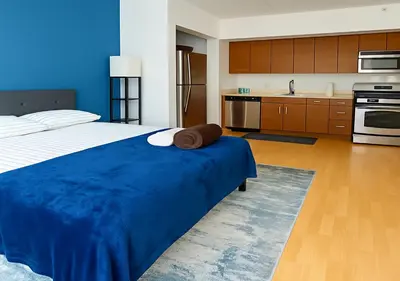 a bedroom with a large blue bed and a kitchen at Studio apart Time Square in New York