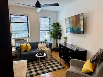 a living room with a blue couch and yellow pillows at Boutique Studio Apartment on Grand Ave in Englewood