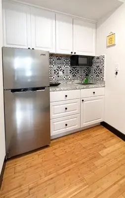 a kitchen with a stainless steel refrigerator and white cabinets at Boutique Studio Apartment on Grand Ave in Englewood