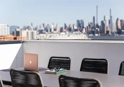 a table and chairs with a laptop on a balcony at Dharma Home Suites Hoboken in Hoboken