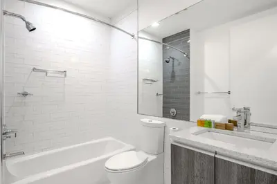a white bathroom with a toilet and a bath tub at Dharma Home Suites Hoboken in Hoboken