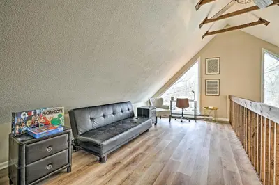a living room with a black leather couch and wooden floors at Golf, Ski and Fish Cabin with Deck in Tobyhanna! in Tobyhanna