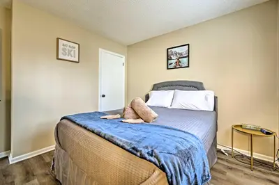 a bedroom with a bed with a blue blanket at Golf, Ski and Fish Cabin with Deck in Tobyhanna! in Tobyhanna
