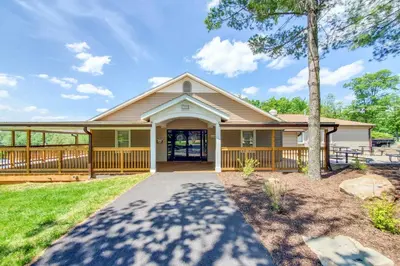 a house with a porch and a tree at Golf, Ski and Fish Cabin with Deck in Tobyhanna! in Tobyhanna