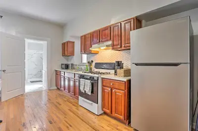 a kitchen with wooden cabinets and a white refrigerator at Updated Bayonne Townhome about 11 Mi to NYC! in Bayonne