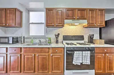 a kitchen with wooden cabinets and a stove top oven at Updated Bayonne Townhome about 11 Mi to NYC! in Bayonne