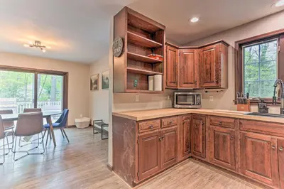 a kitchen with wooden cabinets and a dining room at Updated Stroudsburg Home with Spacious Deck! in Stroudsburg
