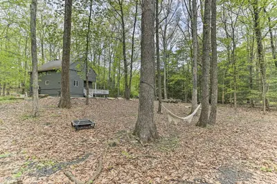 a hammock in the woods next to a house at Updated Stroudsburg Home with Spacious Deck! in Stroudsburg