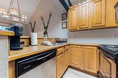 a kitchen with wooden cabinets and a black dishwasher at Unwind in Telstar in Lake Harmony