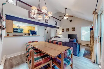 a dining room and living room with a table and a bed at Unwind in Telstar in Lake Harmony