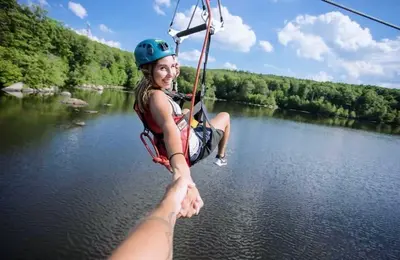 a girl is on a zip line over a river at Mountain Creek Resort at Appalachian Hotel - Pool & Hot Tub in Vernon Township