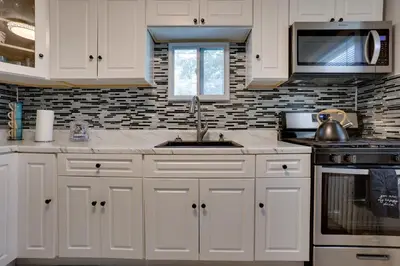 a kitchen with white cabinets and a sink at 11 Mi to Manhattan Pet-Friendly Duplex with Yard! in Teaneck