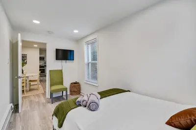 a bedroom with a white bed and a green chair at Luxurious 2BD family friendly, central in Philadelphia