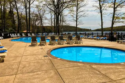 a swimming pool with chairs and a table and water at Big Boulder Bliss in Lake Harmony