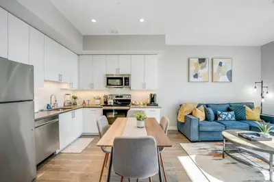 a kitchen and living room with a table and a blue couch at Stylish 1br Unit. Parking. Easy Ride to NYC in Hackensack