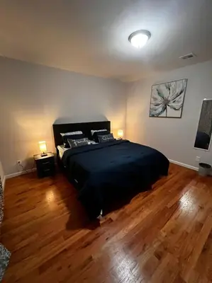 a bedroom with a large black bed and wooden floors at SPRINGVIEW HOMES 12MINS FROM EWR & 3 MINS FROM UNIVERSITY HOSPITAL in Newark