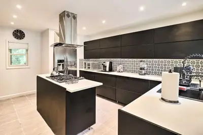 a kitchen with black cabinets and a stove top oven at Chic Long Pond Family Home with Fire Pits and Deck! in Long Pond