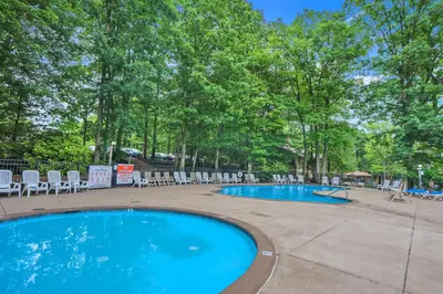 a swimming pool with chairs and tables and trees at Big Boulder Lake Townhome in Lake Harmony
