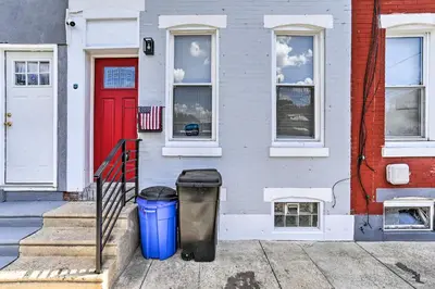 a house with two trash cans and a red door at Philadelphia Townhome Less Than 8 Mi to Center City! in Philadelphia