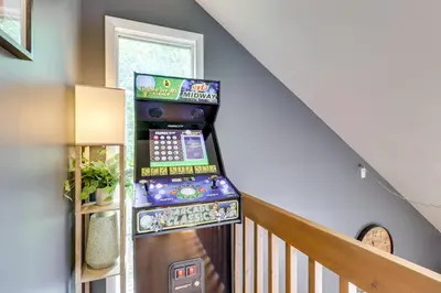 a video game machine in a room with a staircase at Hot Tub, Fire Pit and Barrel Sauna Poconos Abode in Long Pond