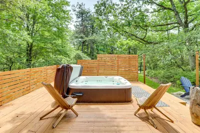 a hot tub on a wooden deck with two chairs at Hot Tub, Fire Pit and Barrel Sauna Poconos Abode in Long Pond