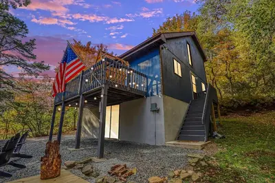 a tiny house with a staircase and an american flag at Hot Tub, Fire Pit and Barrel Sauna Poconos Abode in Long Pond