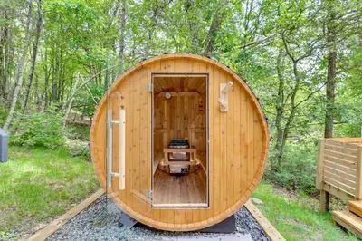 a wooden barrel house with a stove in the woods at Hot Tub, Fire Pit and Barrel Sauna Poconos Abode in Long Pond