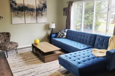 a living room with a blue couch and a table at Lake Access! Catskill Cozy Home- Hot-Tub, Sauna in Loch Sheldrake