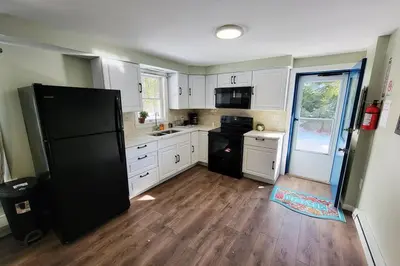 a kitchen with white cabinets and a black refrigerator at Lake Access! Catskill Cozy Home- Hot-Tub, Sauna in Loch Sheldrake