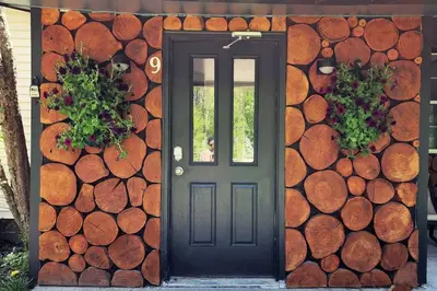 a black door on a house with a wall of logs at Serene 3-Bedroom Home with Dome, Hot Tub, Sauna in Hurleyville
