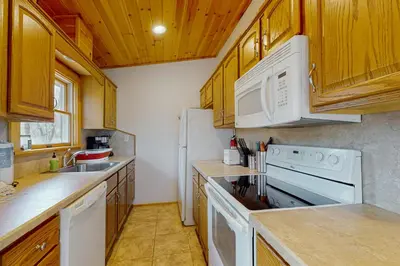 a kitchen with white appliances and wooden cabinets at The Cozy Cabin in Albrightsville