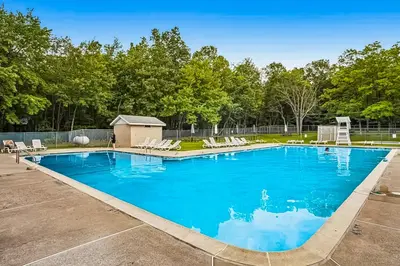 a large swimming pool with lounge chairs in a yard at The Cozy Cabin in Albrightsville