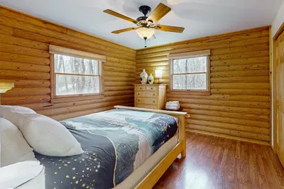a bedroom with wooden walls and a bed with a ceiling fan at The Cozy Cabin in Albrightsville