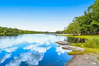 a lake with a reflection of clouds in the water at The Cozy Cabin in Albrightsville