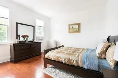 a bedroom with a bed and a dresser with a mirror at Warm 3 BR for U Near Manhattan View, 15 Min to NYC in West New York