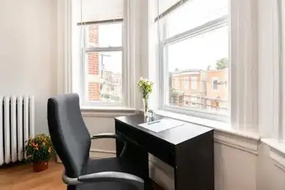 a desk and a chair in a room with two windows at Warm 3 BR for U Near Manhattan View, 15 Min to NYC in West New York