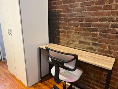 a black chair sitting at a desk next to a brick wall at The Cityline Residences in New York