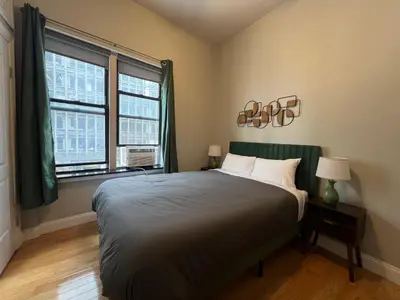 a bedroom with a large bed and two windows at The Cityline Residences in New York
