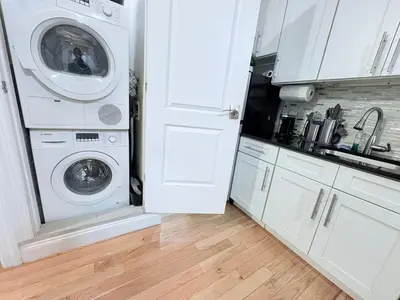 a white laundry room with a washer and dryer at The Cityline Residences in New York