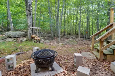 a fire pit in the middle of a forest at Poconos Cabin Serene Deck, Fire Pit and Game Room in Tobyhanna
