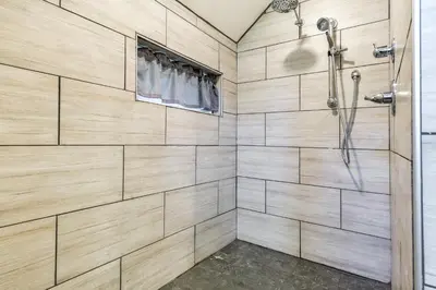 a shower in a bathroom with wooden walls at Pet-Friendly Delta Cabin with Private Hot Tub! in Delta