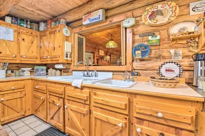 a kitchen with wooden cabinets and a sink in a cabin at Handcrafted Log Cabin in Candor Group Getaway! in Candor