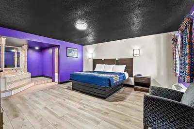 a hotel room with a bed and purple walls at Red Carpet Inn and Suites in Bellmawr