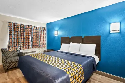 a bedroom with a bed and a blue wall at Red Carpet Inn and Suites in Bellmawr