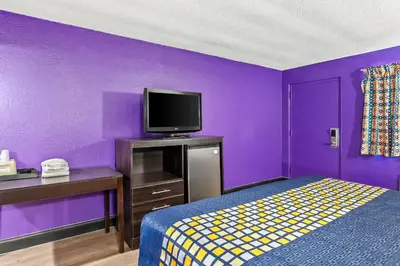 a purple bedroom with a bed and a tv at Red Carpet Inn and Suites in Bellmawr