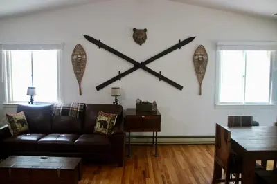 a living room with a brown leather couch and a wall with axes at Escape to a 3-Bedroom Cabin in Lower Catskills in Woodridge