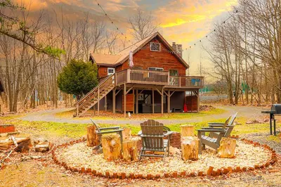 a log cabin with a table and chairs in front of it at March Giveaway: 3 Nights equal $50 Activity Credit in Albrightsville