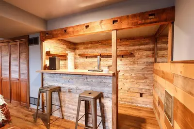 a bar in a kitchen with wooden walls and stools at March Giveaway: 3 Nights equal $50 Activity Credit in Albrightsville