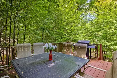 a wooden table with a vase of flowers on a deck at Chic Tobyhanna Home with Furnished Deck Space! in Tobyhanna