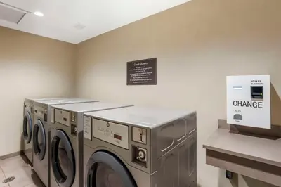 a laundry room with three washing machines and a sign at Sleep Inn North - Central York in York